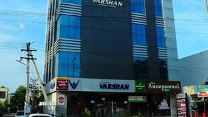 A modern building with a prominent 'VARSHAN INTERNATIONAL' sign, featuring a glass facade and a flat roof. - Hotel Varshan International (Erode)
