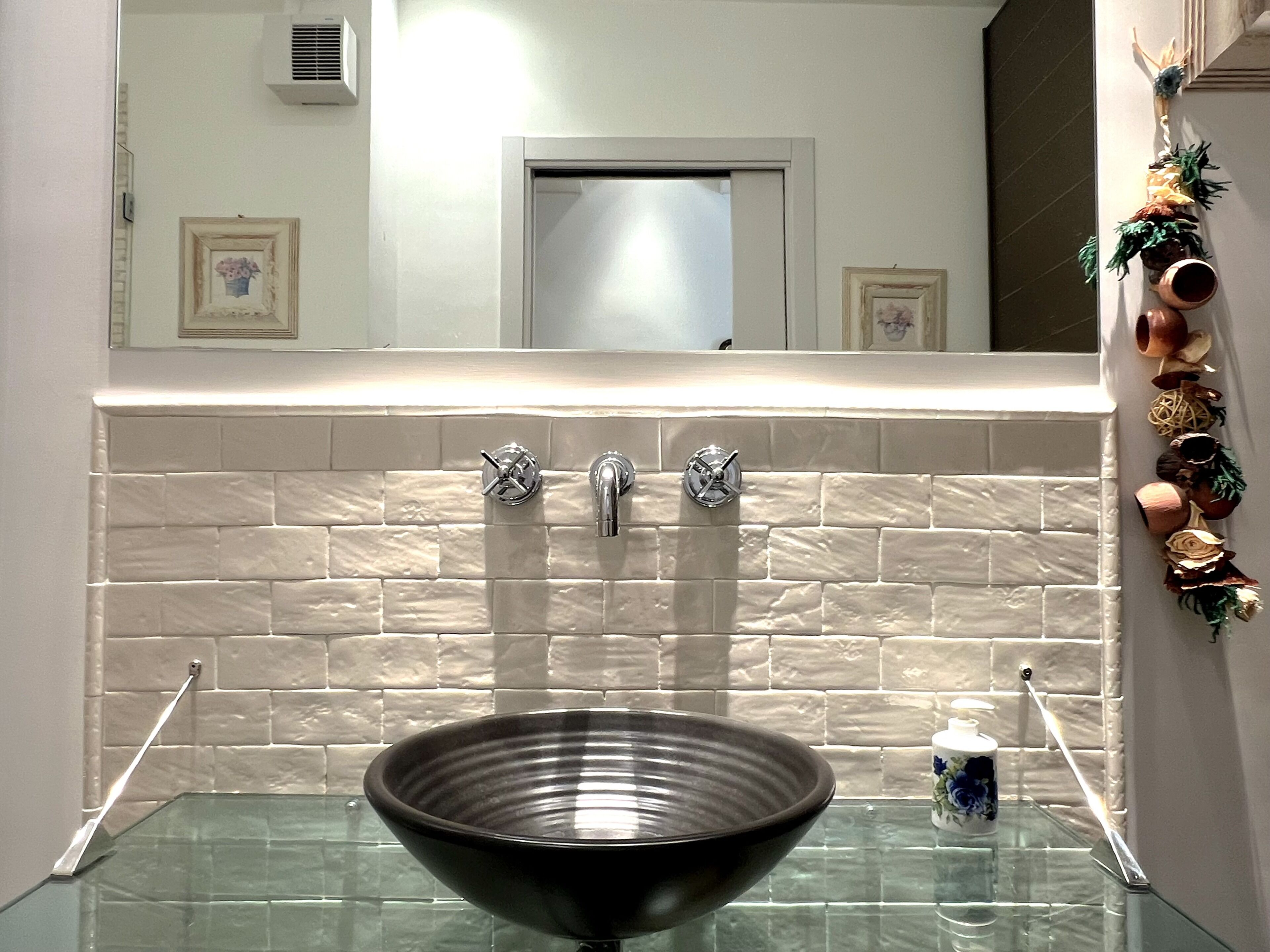 A bathroom with a glass sink, two faucets, and a mirror above.