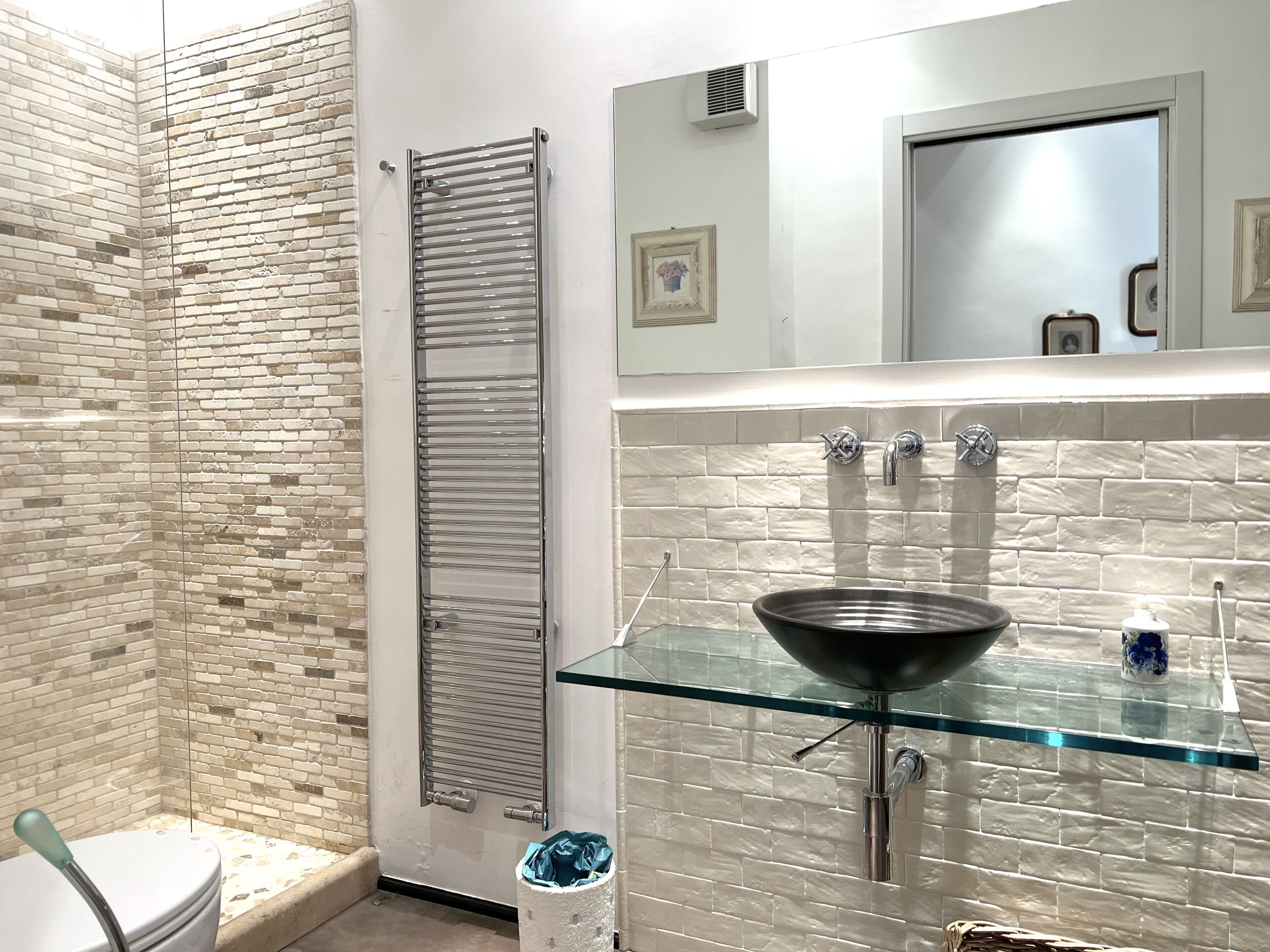 A bathroom with a glass sink, a towel rack, and a mirror.