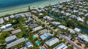 An aerial view of a coastal residential area with houses, a clear blue sea, and a small river.
