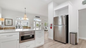 A modern kitchen with white cabinetry, stainless steel appliances, and a large island.
