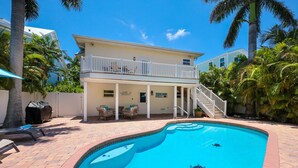 A two-story house with a pool, outdoor furniture, and a covered patio area.