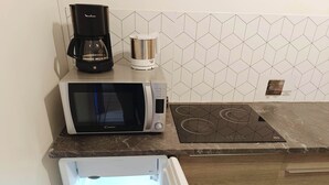 Une cuisine équipée d’un four à micro-ondes, d’une machine à café et d’une plaque de cuisson à induction intégrée.