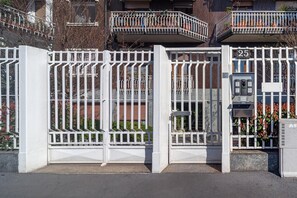 Une entrée fermée par un portail, avec un panneau indiquant le numéro 25, un clavier pour le système de sécurité et une petite boîte aux lettres.