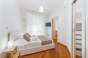 Une chambre à coucher moderne avec un lit, une table de chevet et un téléviseur fixé au mur.