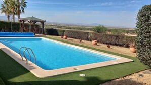 Ein rechteckiger Swimmingpool mit blauer Innenseite, umgeben von grünem Kunstrasen.