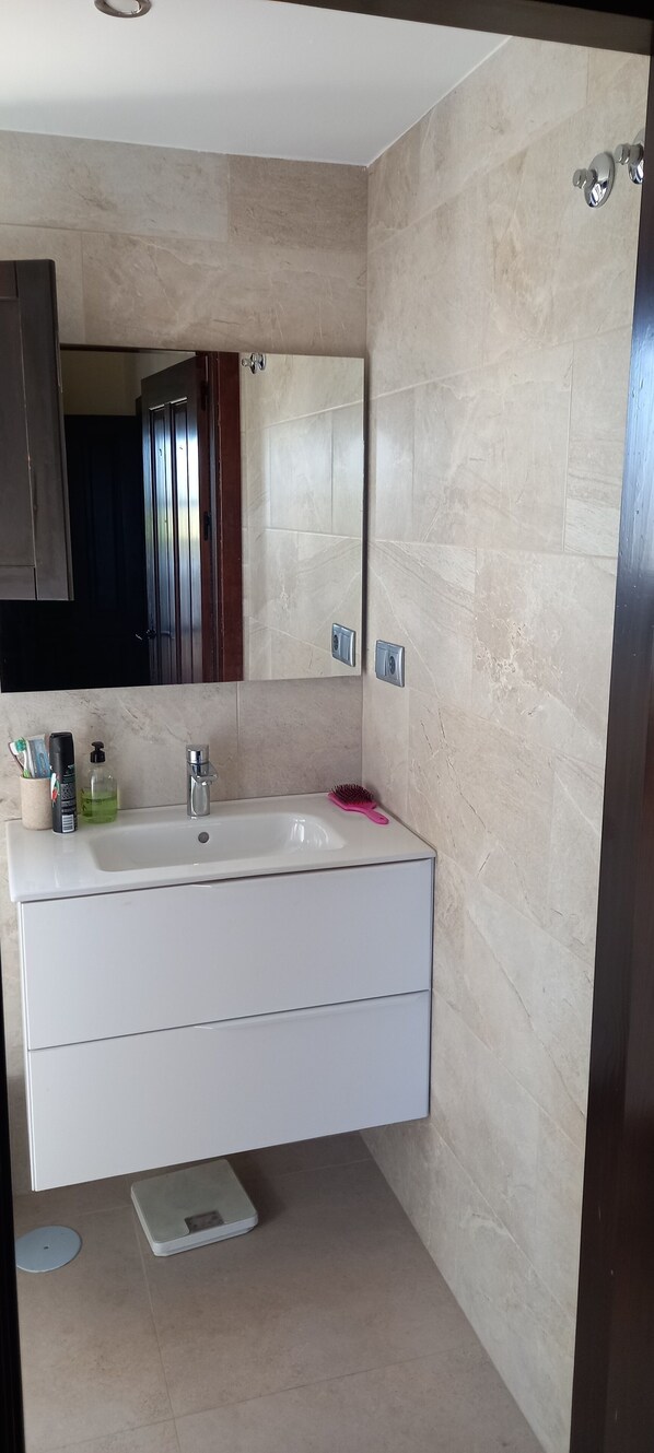 Une salle de bain moderne avec un meuble-lavabo blanc, un grand miroir et un espace douche.