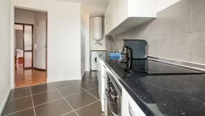 A modern kitchen with a black countertop, white cabinets, and a built-in oven. - GuestRoom by Hoa-Space (Albufeira)