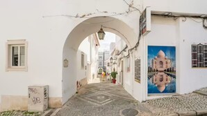 A narrow street with a white building, a large archway, and a mural of a famous building. - GuestRoom by Hoa-Space (Albufeira)