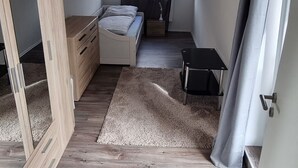 Una camera da letto con un letto, una scrivania, una sedia, uno specchio e una finestra con tende.