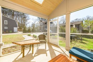 A covered patio with a table and chairs, large windows, and a view of a residential area. - Harry's Handicap Accessible Tea House (Charlotte)