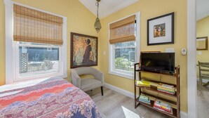 A bedroom with a bed, a chair, a bookshelf, and a television. - Harry's Handicap Accessible Tea House (Charlotte)