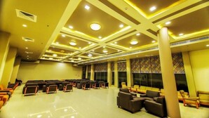 A spacious hall with rows of seating, a high ceiling with recessed lighting, and patterned wall designs.