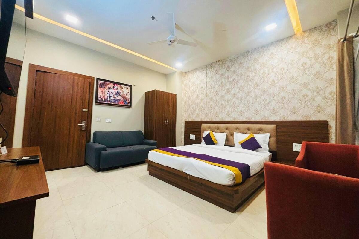 A hotel room with a bed, a desk, a sofa, and a wardrobe.
