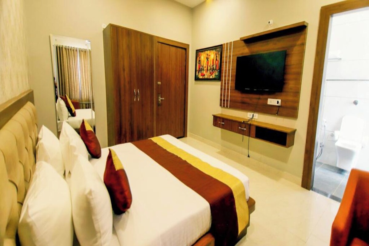 A hotel room with a bed, a television mounted on the wall, and a wardrobe.