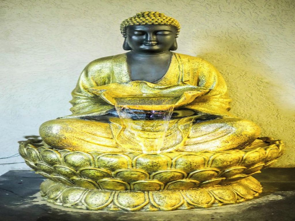 Eine Statue einer sitzenden Figur auf einem Lotusfuß.