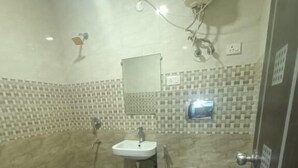 A small bathroom with a white sink, a toilet, and a shower head. - Hotel Royal Inn (New Delhi)