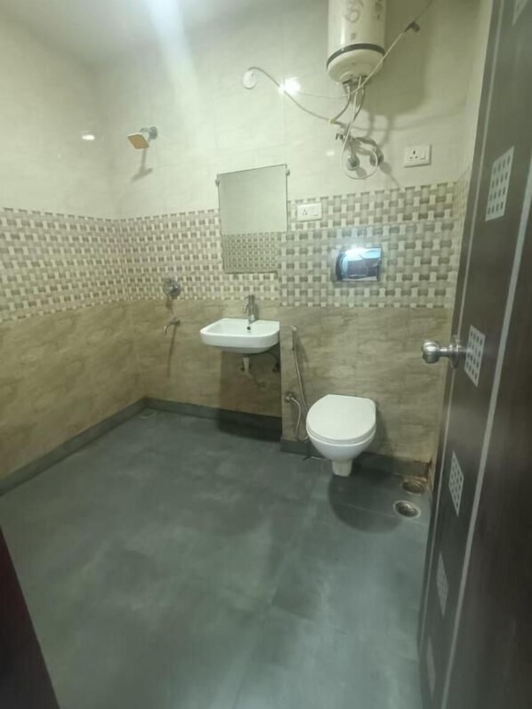 A small bathroom with a white sink, a toilet, and a shower head.