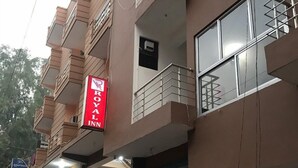A multi-story building with a red sign for a Royal Inn. - Hotel Royal Inn (New Delhi)