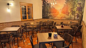 Un restaurante con paredes de ladrillo, mesas de madera, sillas de mimbre y un mural de un viñedo.