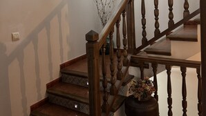 Una escalera de madera con balaustres y barandilla, que lleva a un piso superior.