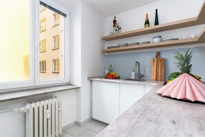 Eine moderne Küche mit weißen Schränken, einer Marmorarbeitsplatte und einem Fenster mit Blick auf ein Gebäude.