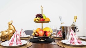 Un présentoir à fruits à trois niveaux, avec une base dorée, entouré d’assiettes, de verres et d’un seau à champagne.