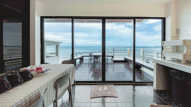 Una habitación con un amplio ventanal corredero que da a un balcón con vistas al mar.