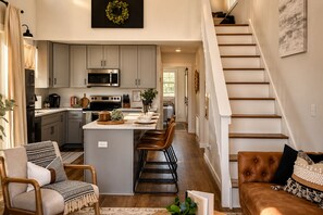 A spacious living area with a kitchen, a staircase, and a dining area. - Calm Waters at The Retreat at Water's Edge (Tracy City)