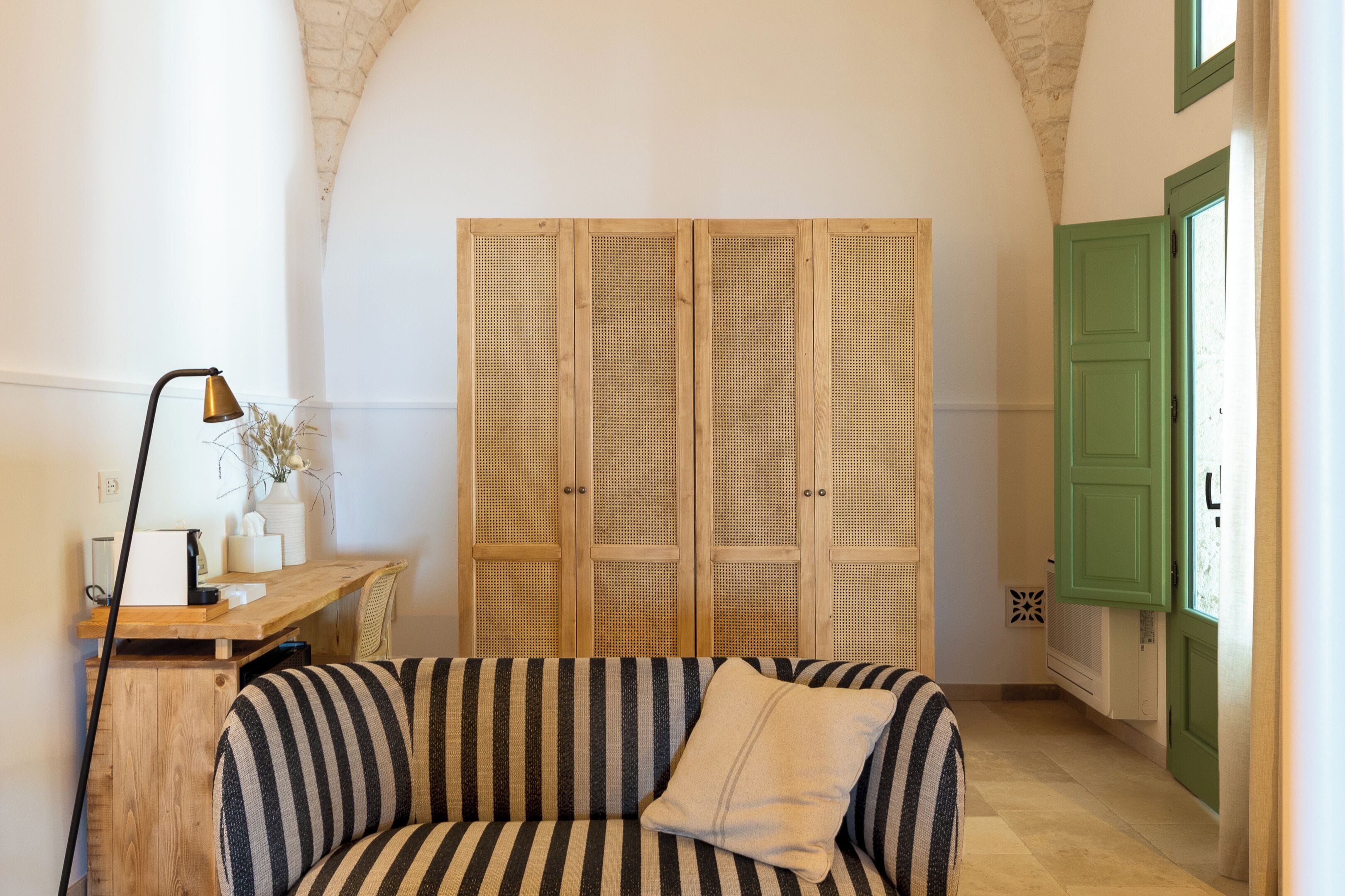 Ein gemütliches Zimmer mit einem gestreiften Sofa, einem Holztisch und einem Rattanschrank.