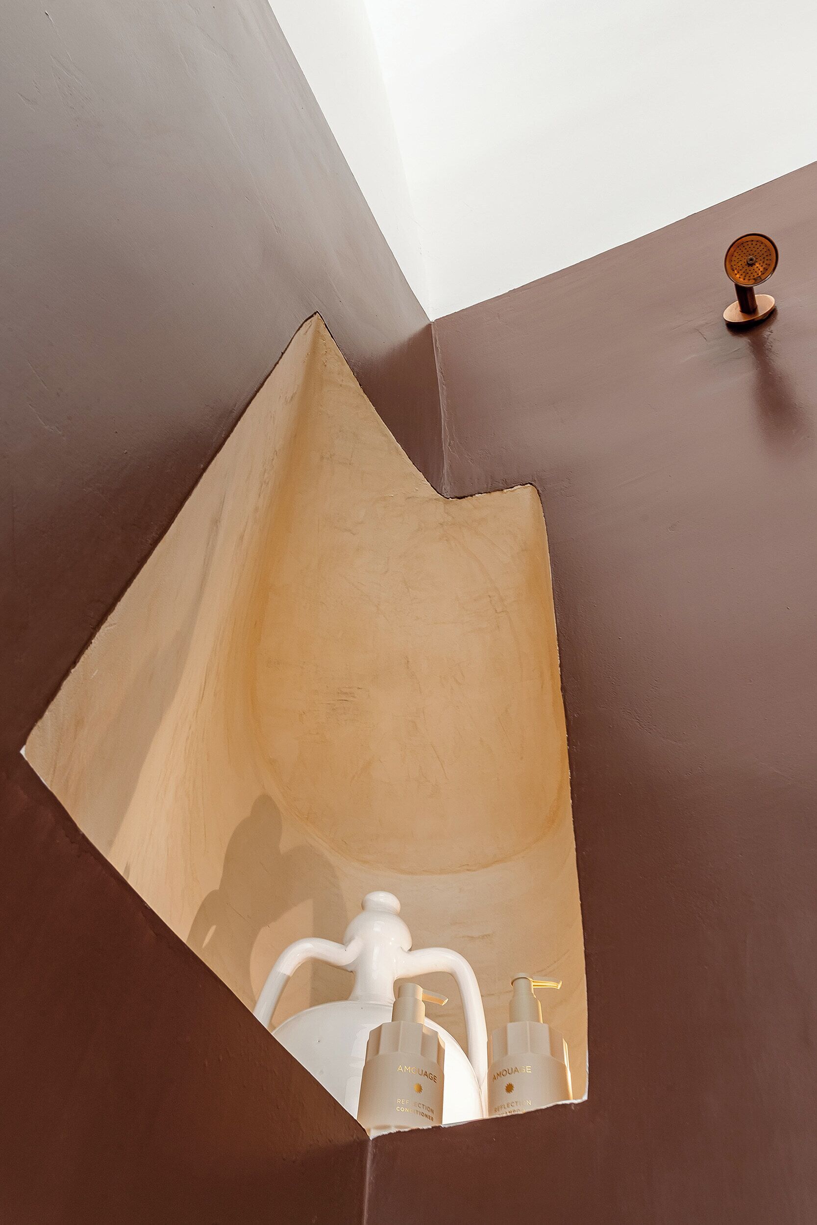 A bathroom with a unique geometric mirror design and a small wooden object on the wall.