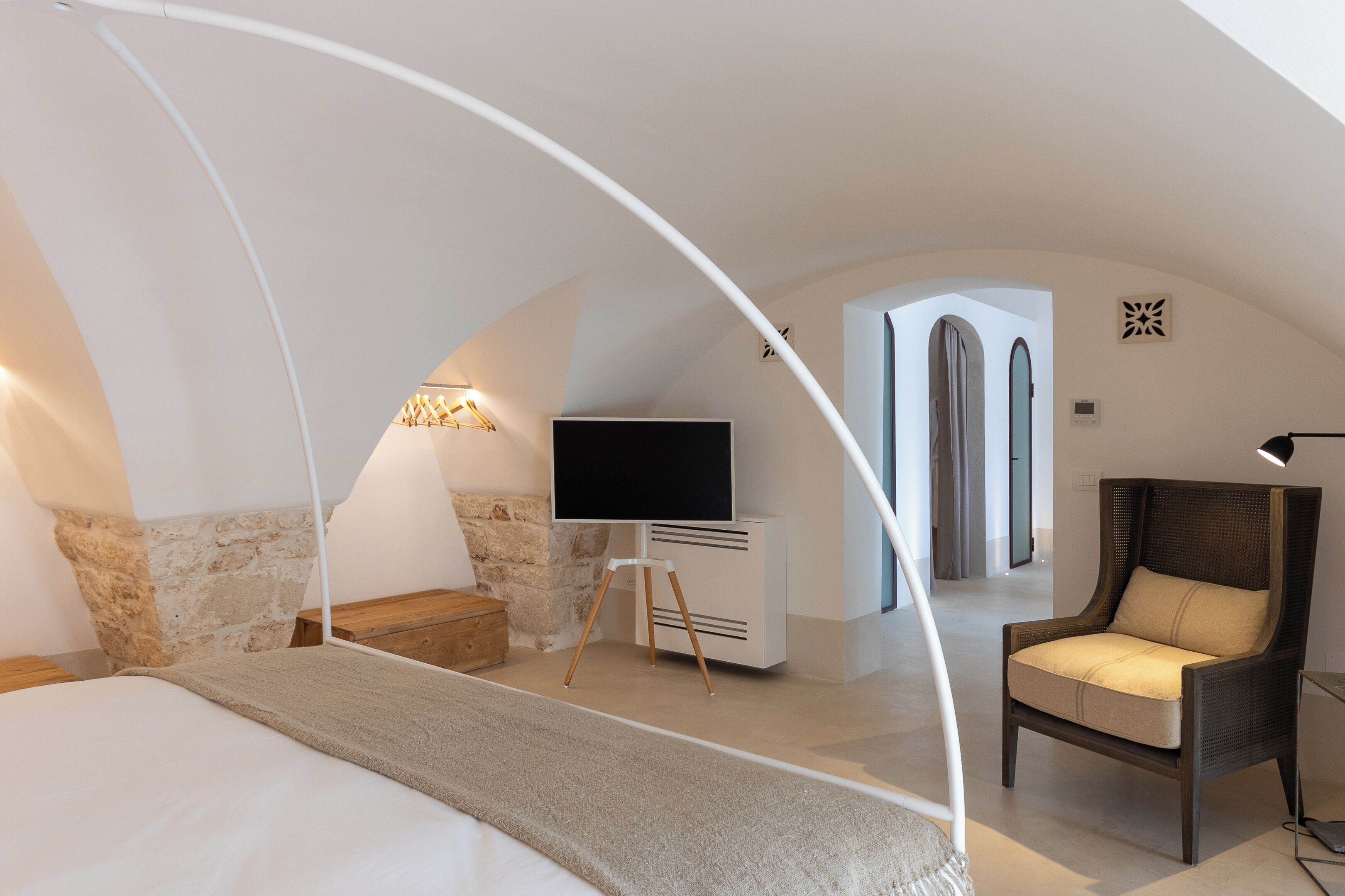 Een moderne slaapkamer met een groot bed, een televisie op een standaard, een stoel en een stenen muur.