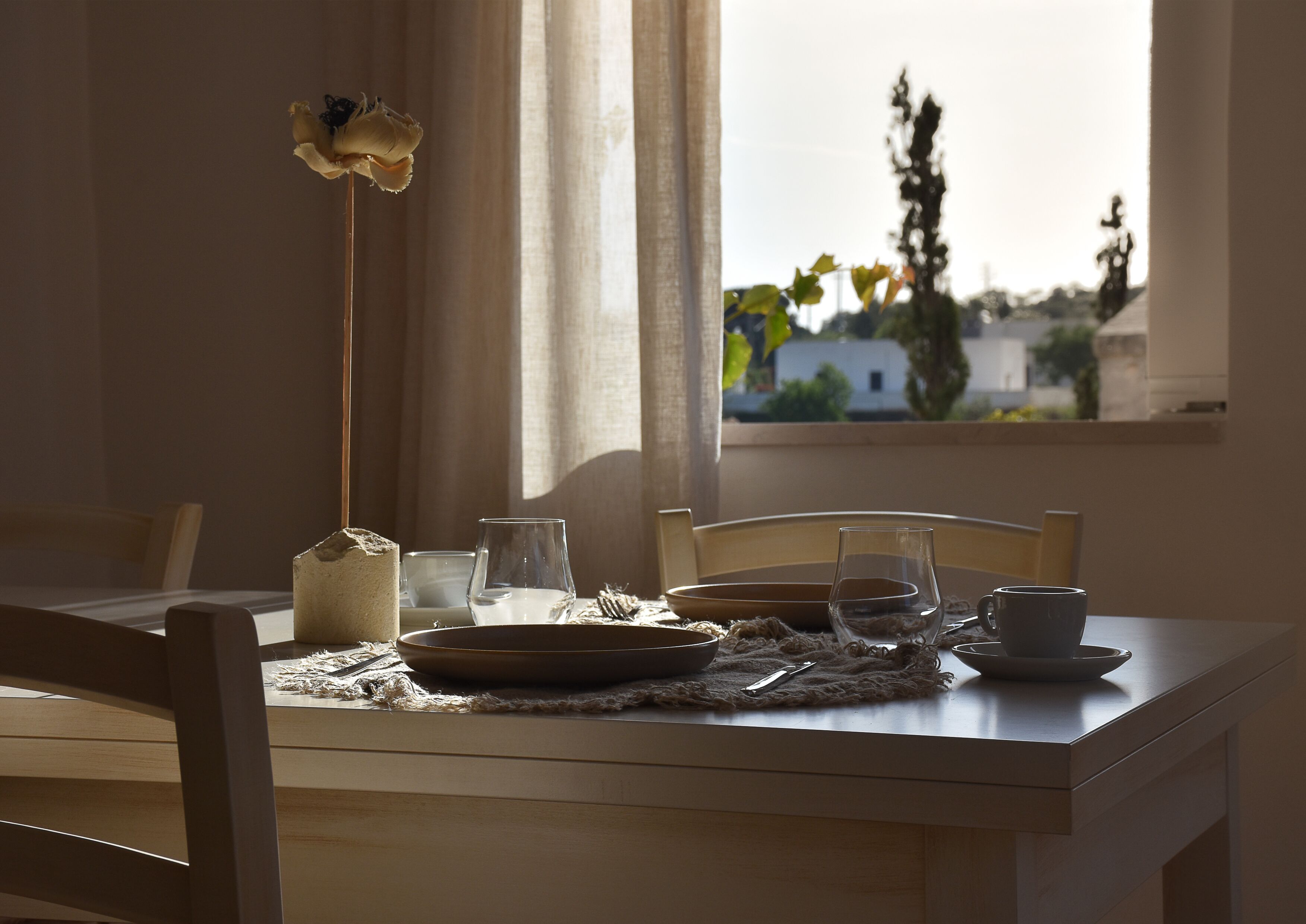 Une table à manger avec un vase, des assiettes et des verres.