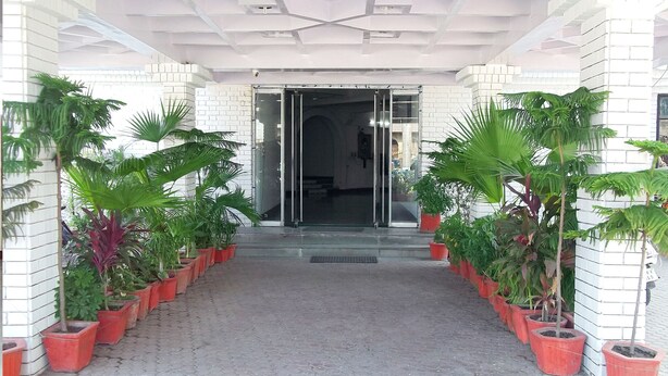 A building entrance with a tiled facade, a glass door, and a central staircase leading to the entrance. - Rahi Motel (Haridwar)