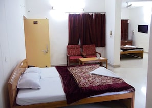 A room with a bed, a chair, a small table, and a mirror. - Rahi Motel (Haridwar)
