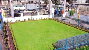 A well-maintained lawn with a blue metal fence and potted plants. - Rahi Motel (Haridwar)