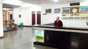A reception area with a reception desk, a clock, and framed pictures on the wall. - Rahi Motel (Haridwar)