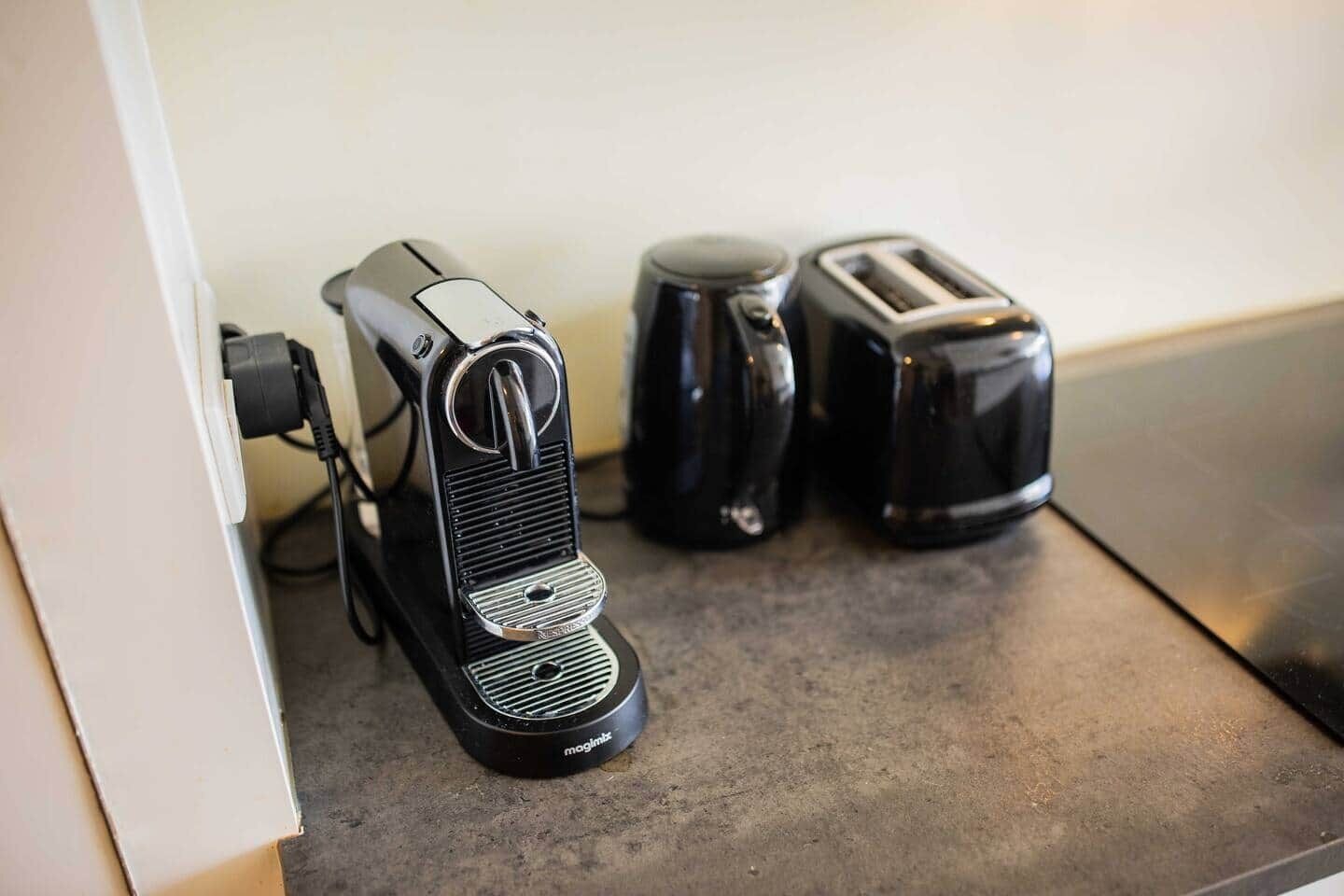 Une machine à café, un grille-pain et une bouilloire sur un plan de travail de cuisine.