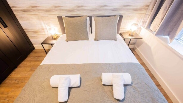 Ein Hotelzimmer mit Bett, zwei Kissen, Nachttischlampen und einem Fenster.