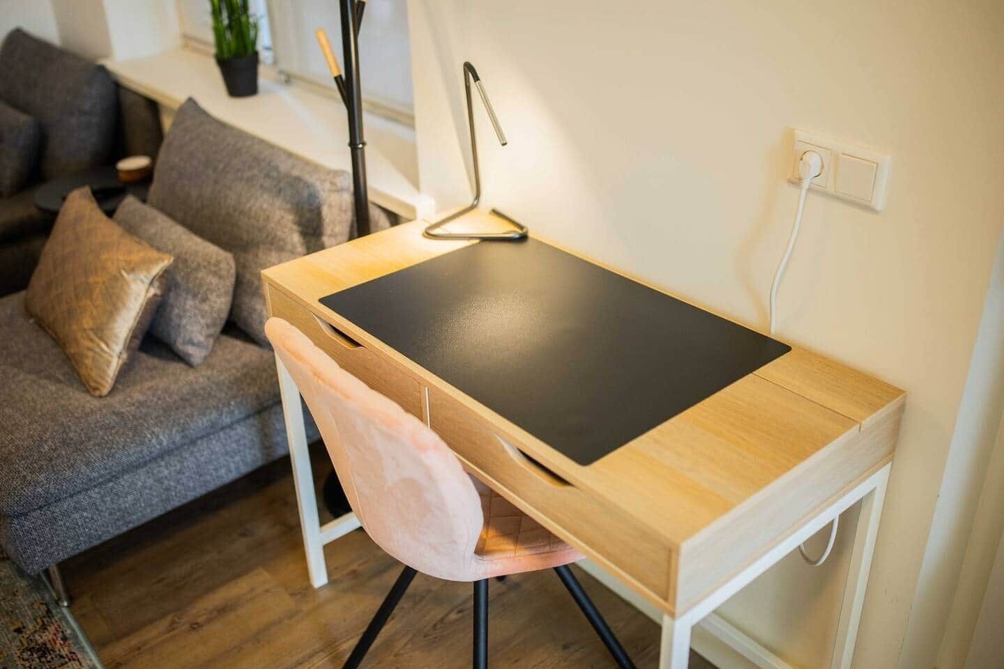 Un espace de travail compact doté d’un bureau en bois, d’un plan de travail noir et d’une chaise blanche.