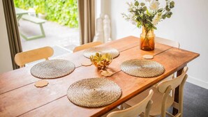 A wooden dining table with woven placemats, a vase with flowers, and chairs. - Superb 90m² Apartment with Garden (KS-8-A) (Eindhoven)