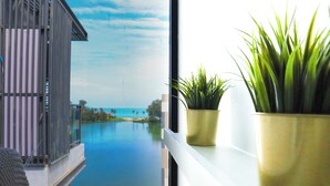A balcony with a view of a calm body of water and a distant shoreline. - Cassia Residences by NLA (Choeng Thale)