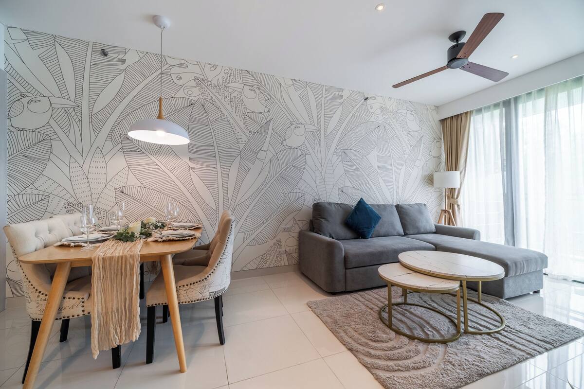 A modern living room with a dining area, grey sofa, and a ceiling fan.