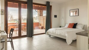 Un dormitorio con cama, escritorio y vistas al exterior a través de un ventanal corredero.