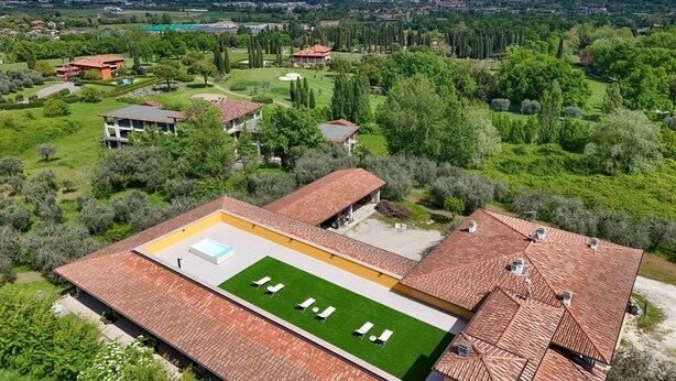 Zona residencial con una casa grande que tiene piscina en la azotea y cancha de tenis.