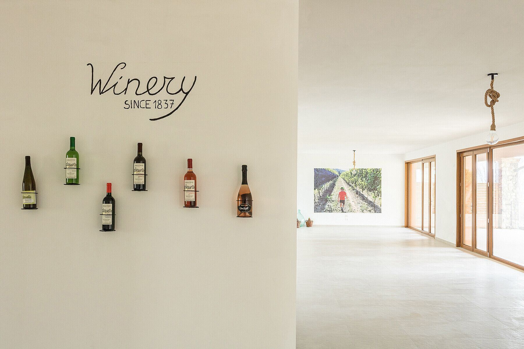 A wall with the text "Winery SINCE 1837" and five wine bottles.