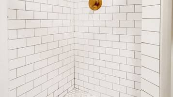 Une douche d’angle avec des carreaux de métro blancs et un sol recouvert de carreaux hexagonaux.
