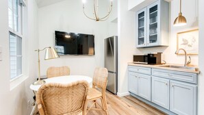 Una cocina moderna con comedor, que incluye un refrigerador de acero inoxidable, un televisor de pantalla plana y armarios azul claro.