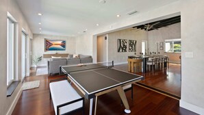 Un'ampia zona giorno con tavolo da ping pong, divano e tavolo da pranzo con sedie.