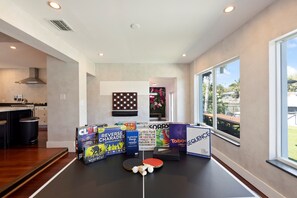 A modern kitchen with a dining area featuring board games and a ping pong table.